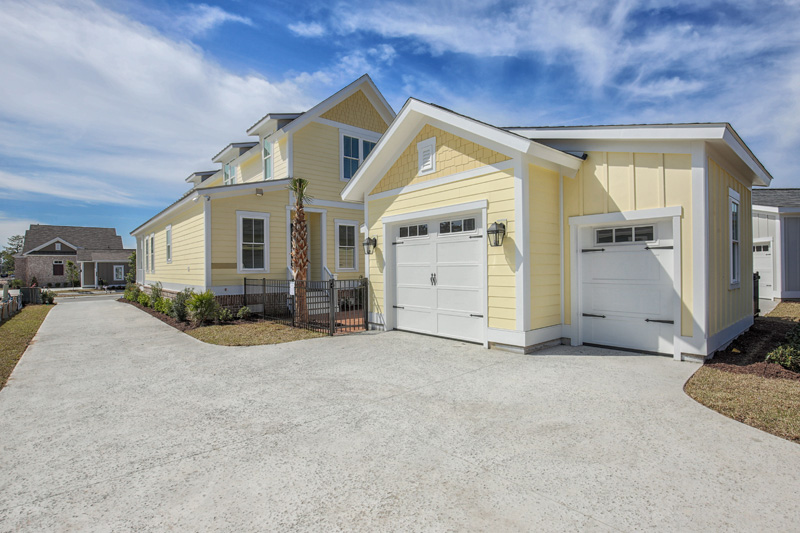 Yellow house and detached garage near black fence