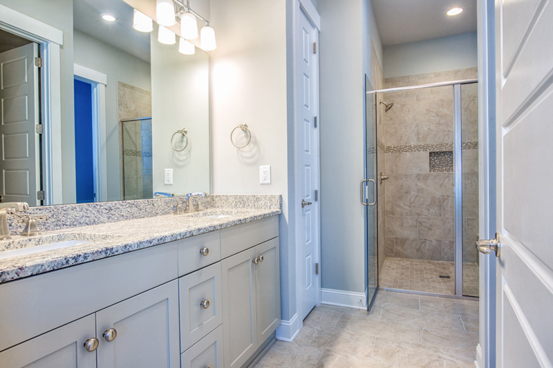 White cabinets and light counters on dual sink vanity near walk in shower