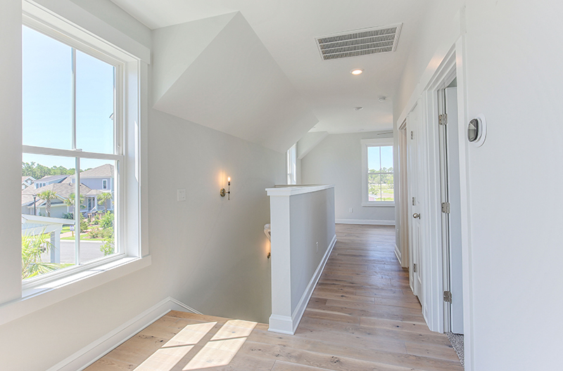 Looking down a hall with wood flooring near bright windows